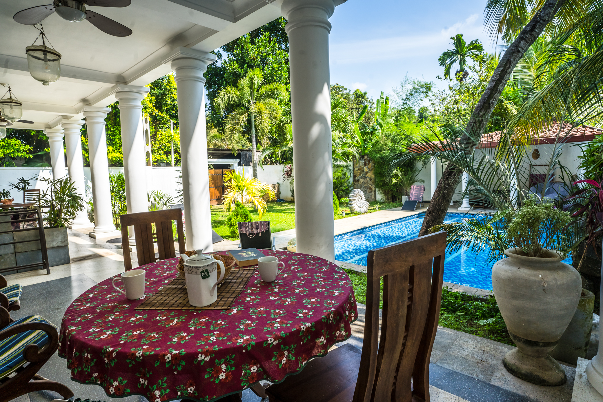A shaded outdoor dining table overlooking Annavilla's garden and pool